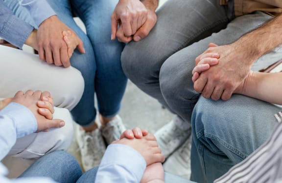 Group of people sitting in a circle and holding hands